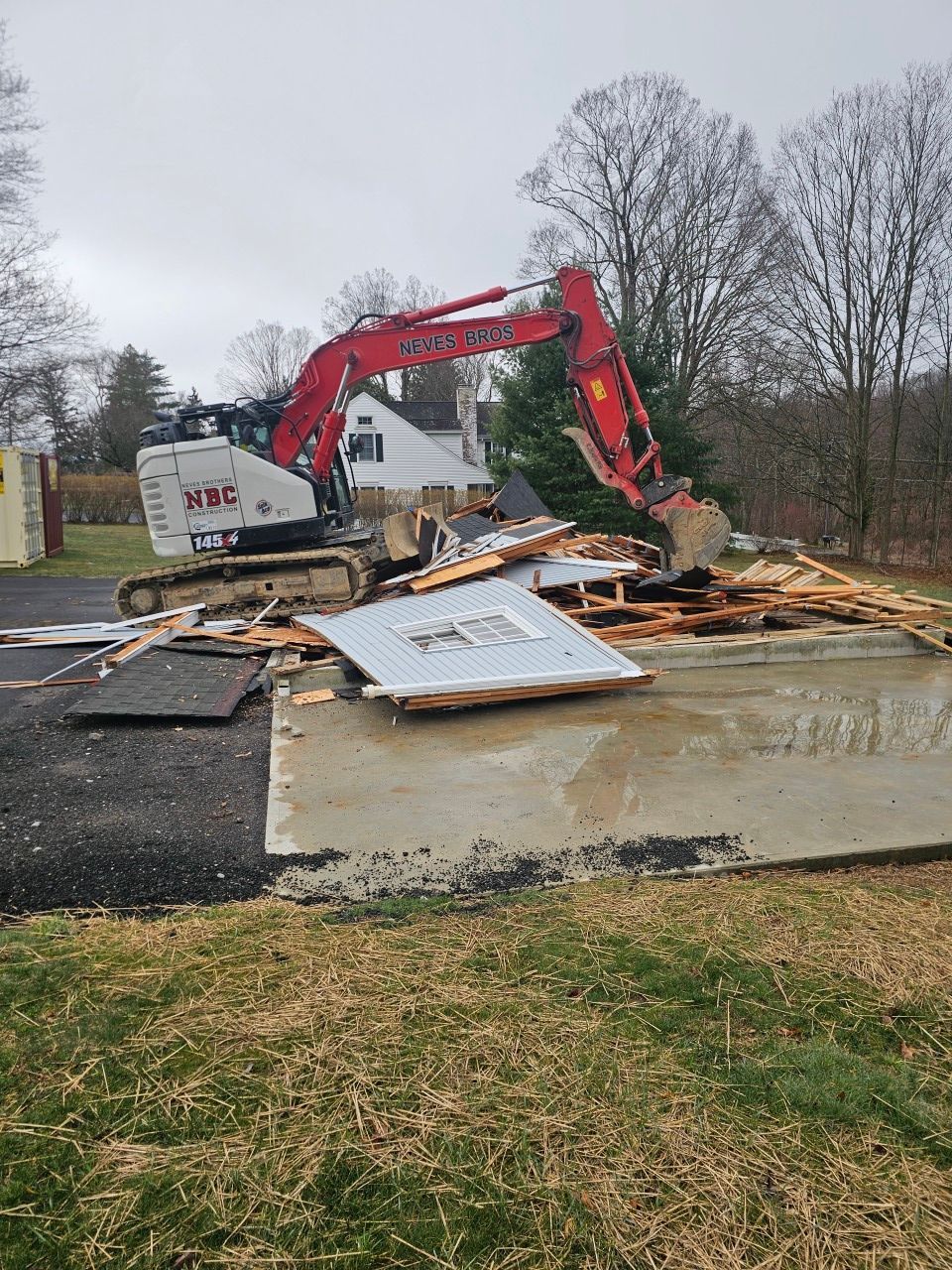 An excavator is destroying a building in a field.