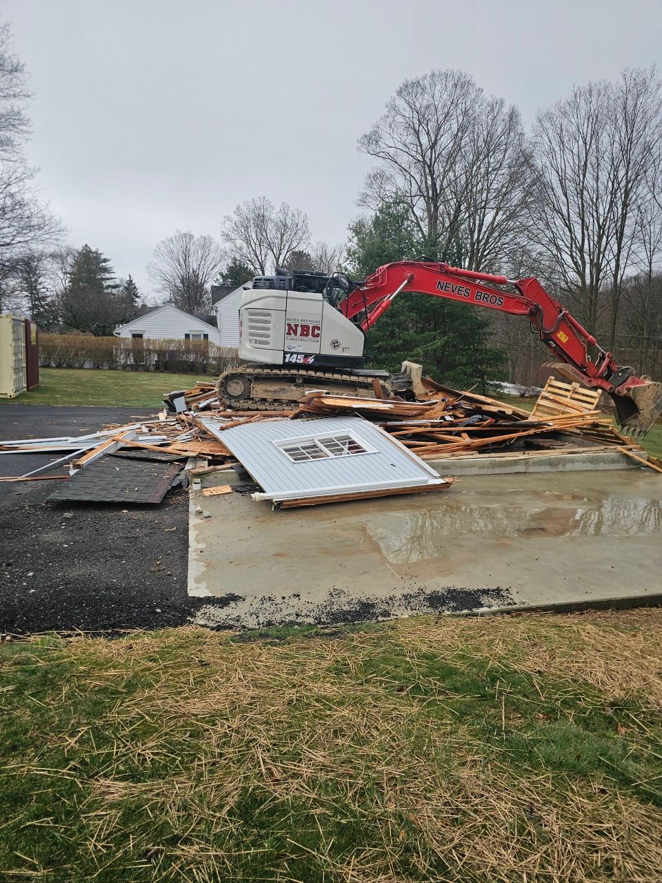A large excavator is demolishing a building in a yard.