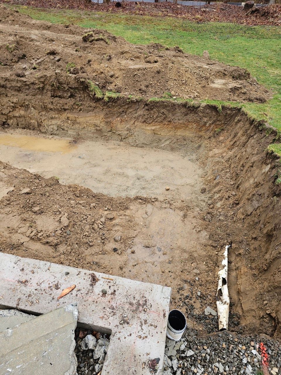 A large hole in the ground is being filled with dirt and grass.