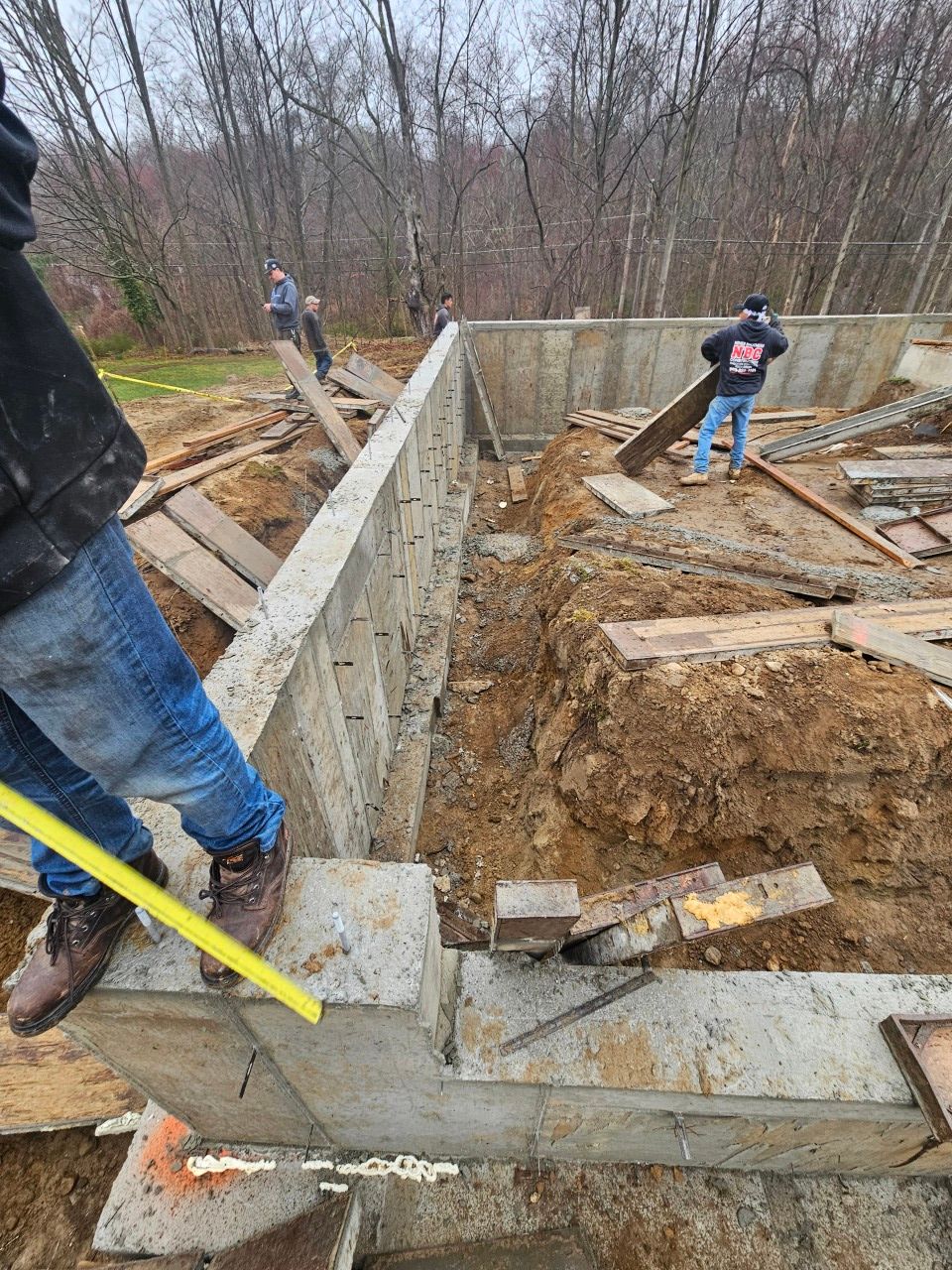 A group of construction workers are working on a concrete wall.