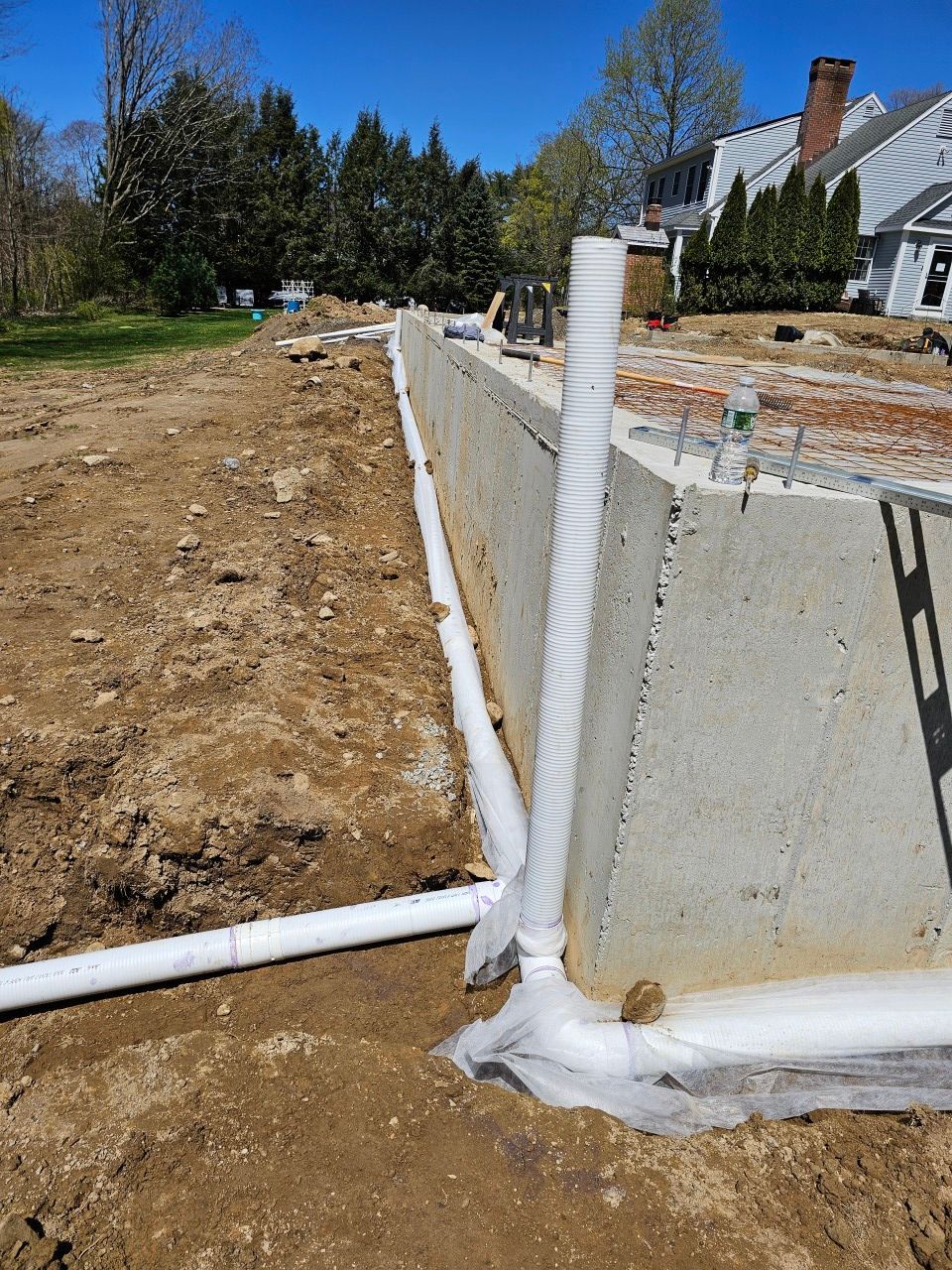 A drainage system is being installed on the side of a concrete wall.