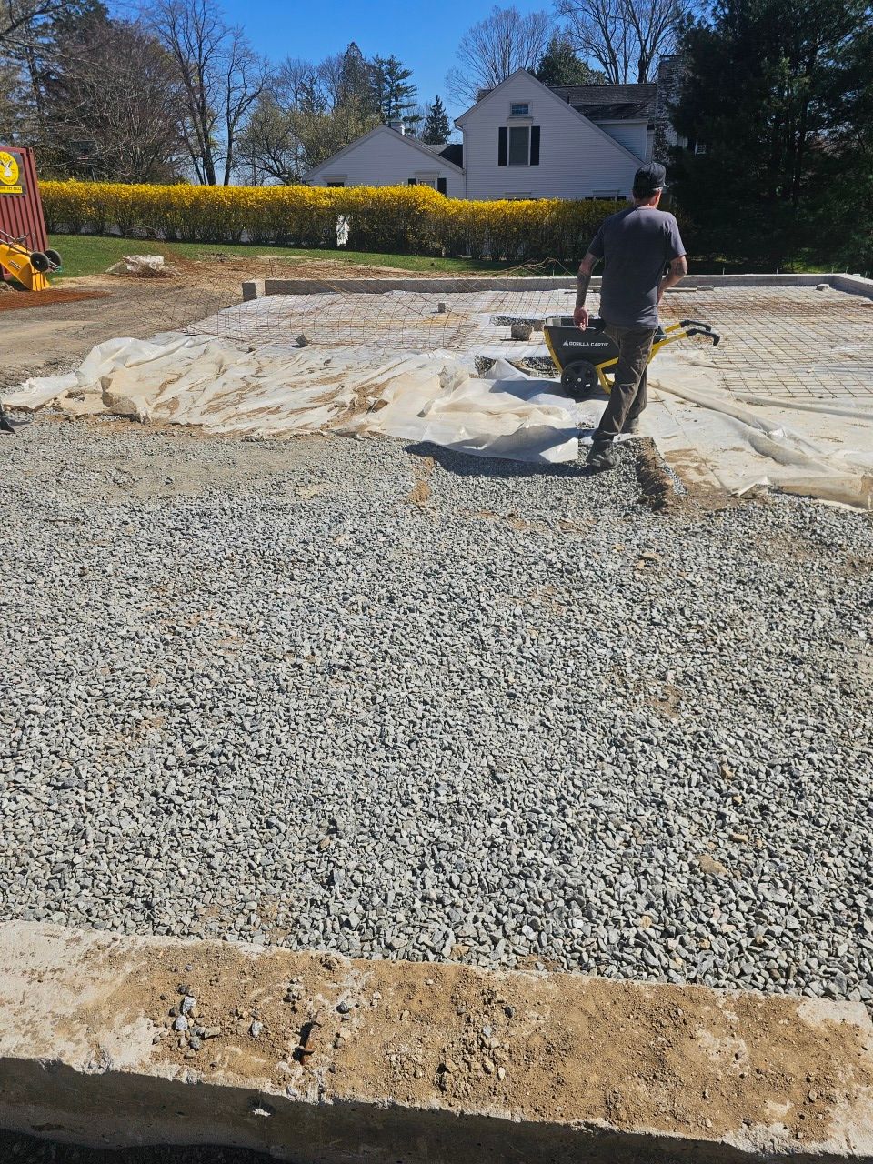 A man is pushing a wheelbarrow on a gravel road