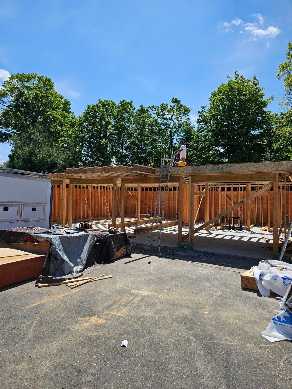 A house is being built on a sunny day with trees in the background.