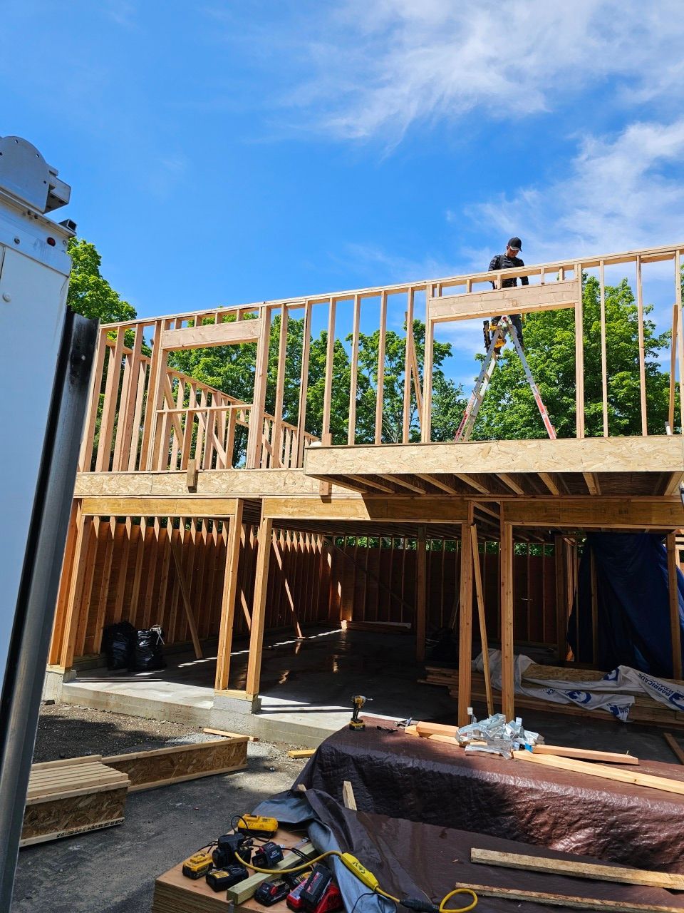 A man is standing on a ladder on top of a building under construction.