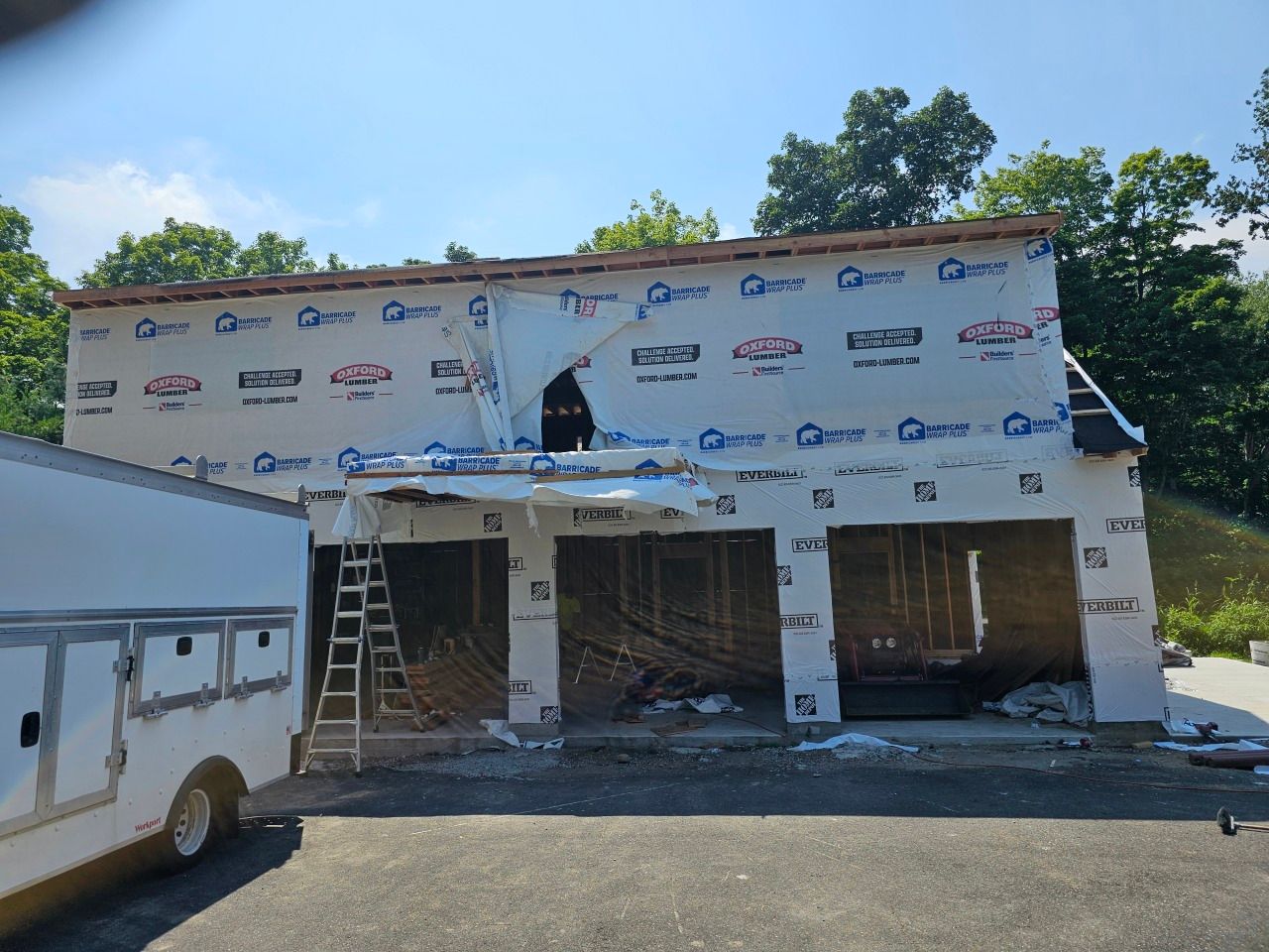 A white truck is parked in front of a building under construction.