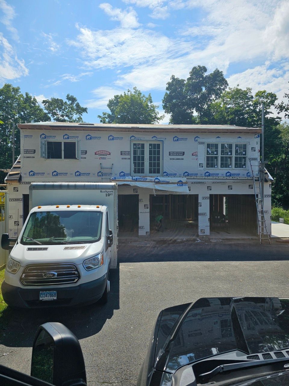 A white van is parked in front of a house under construction.