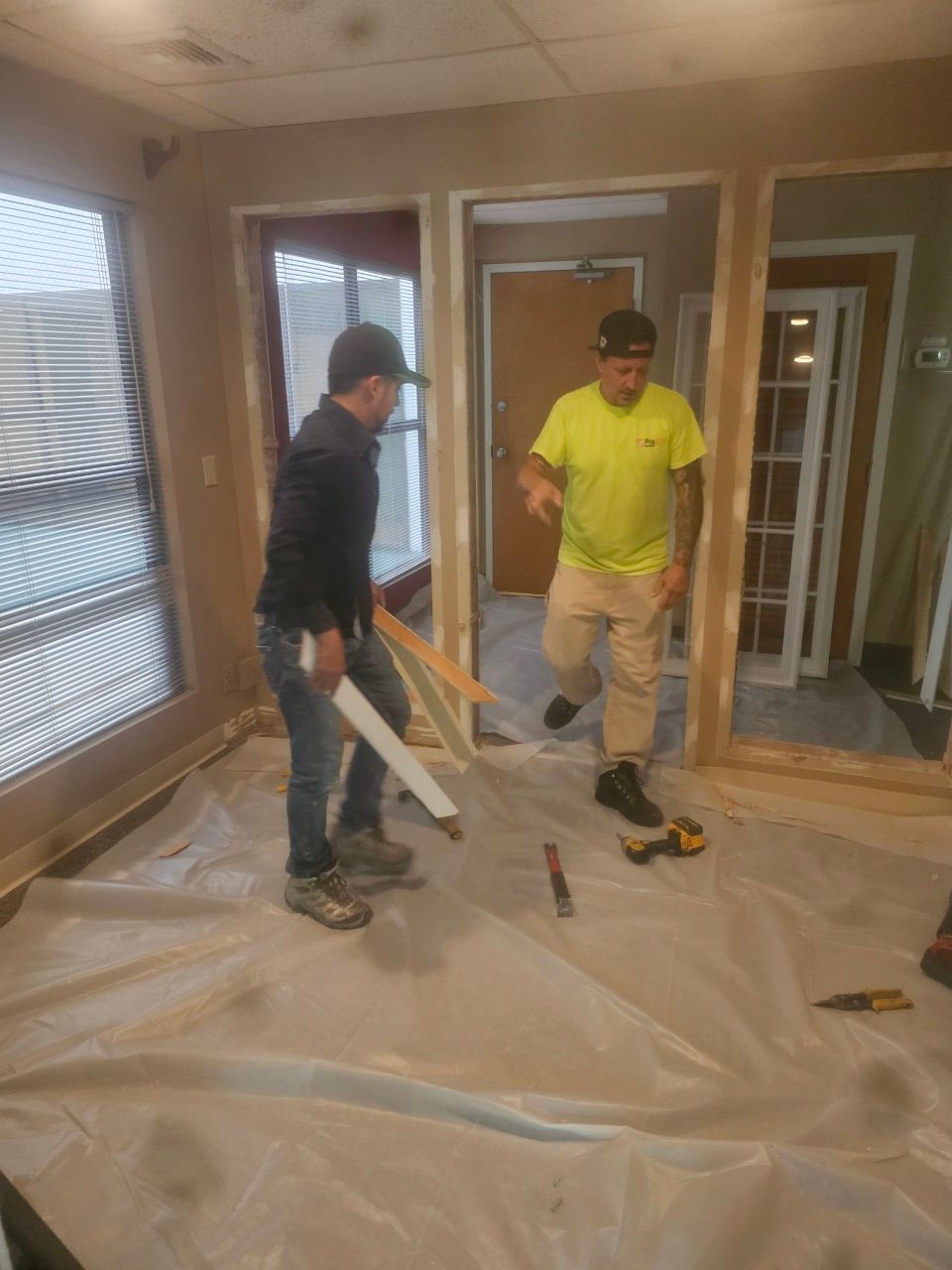 Two men are standing in a room holding pieces of wood.