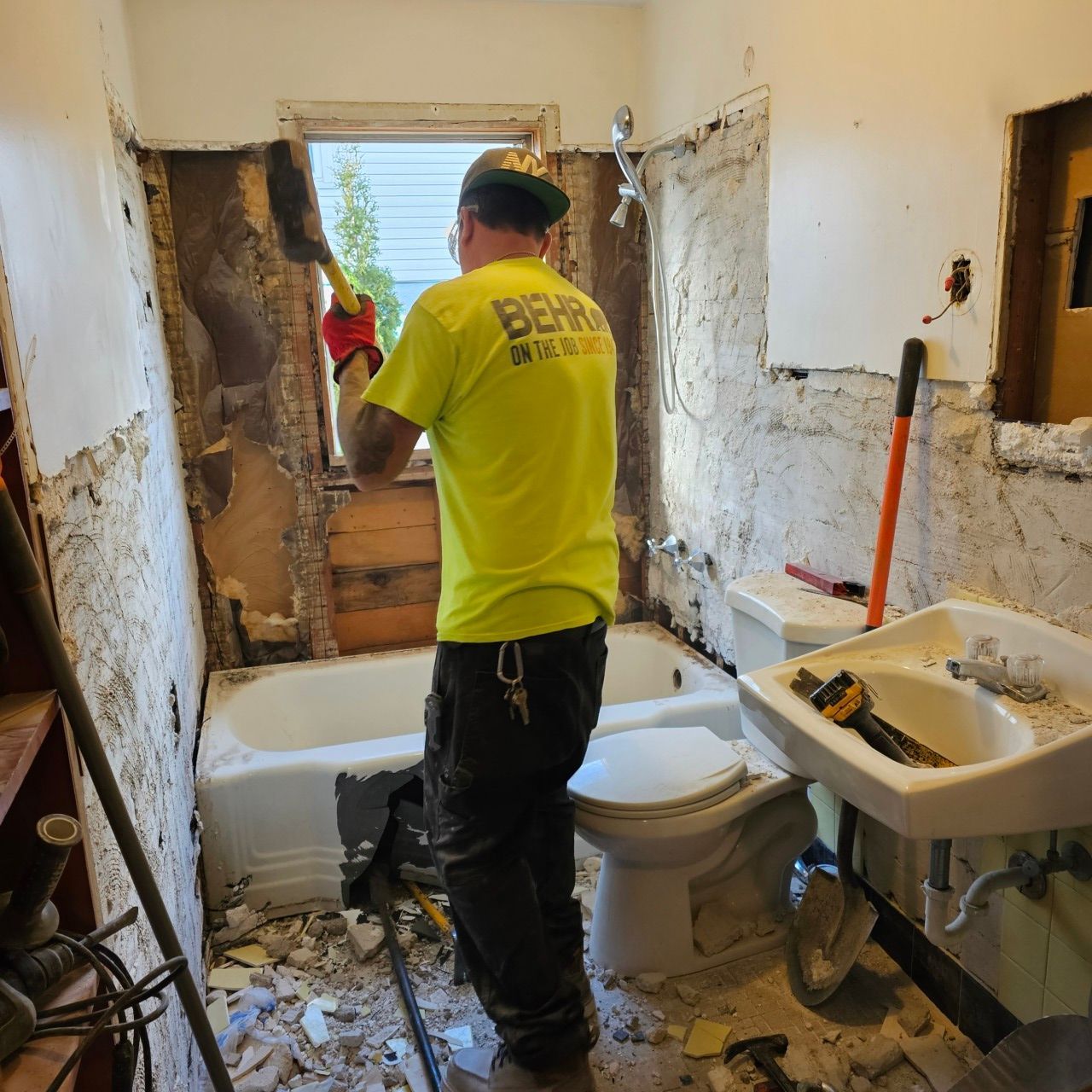 A man in a yellow shirt is working in a bathroom