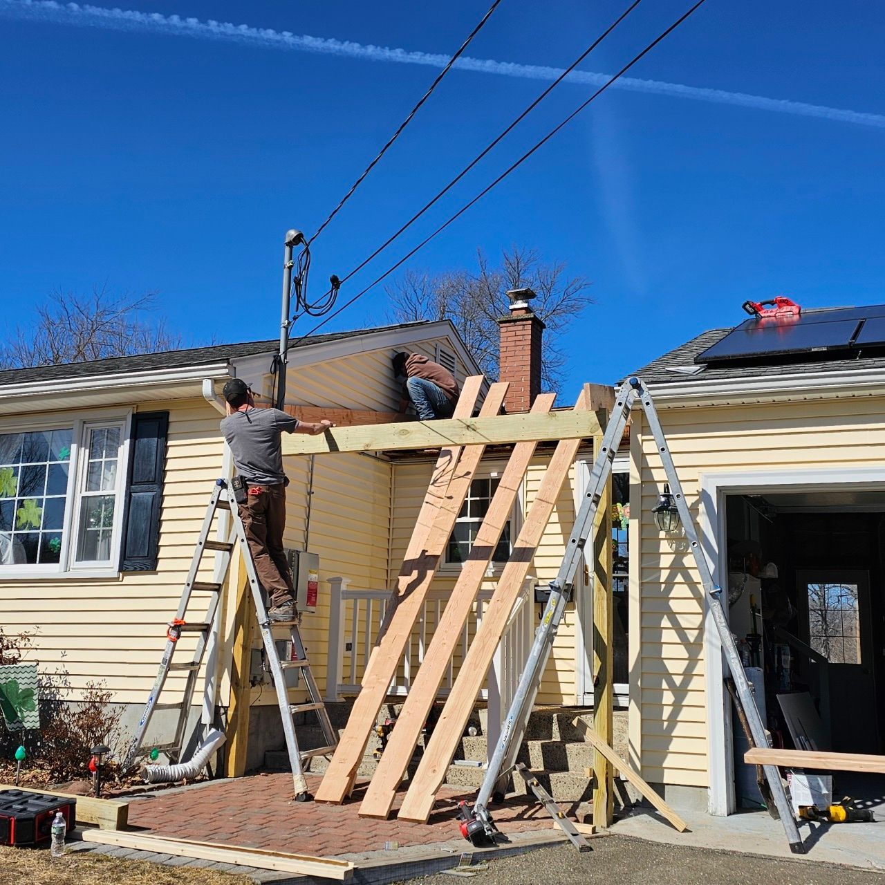 A man on a ladder is working on the side of a house