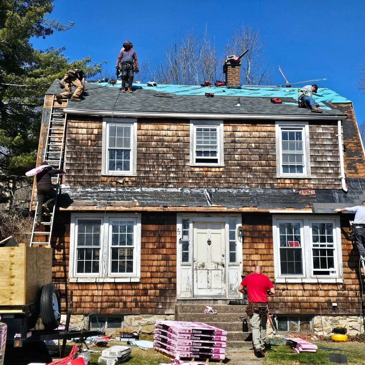 A group of people are working on the roof of a house