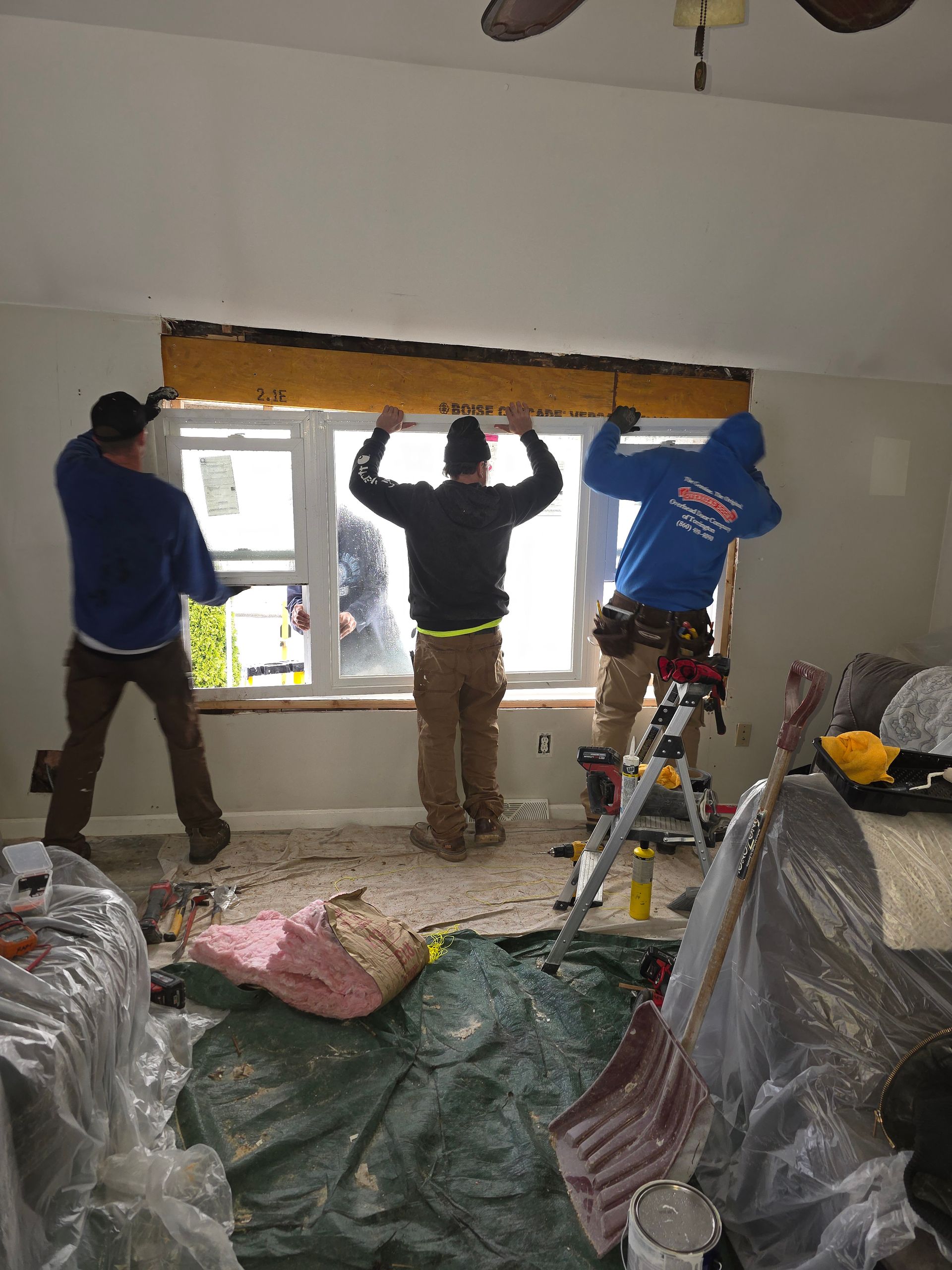 A group of men are working on a window in a living room.