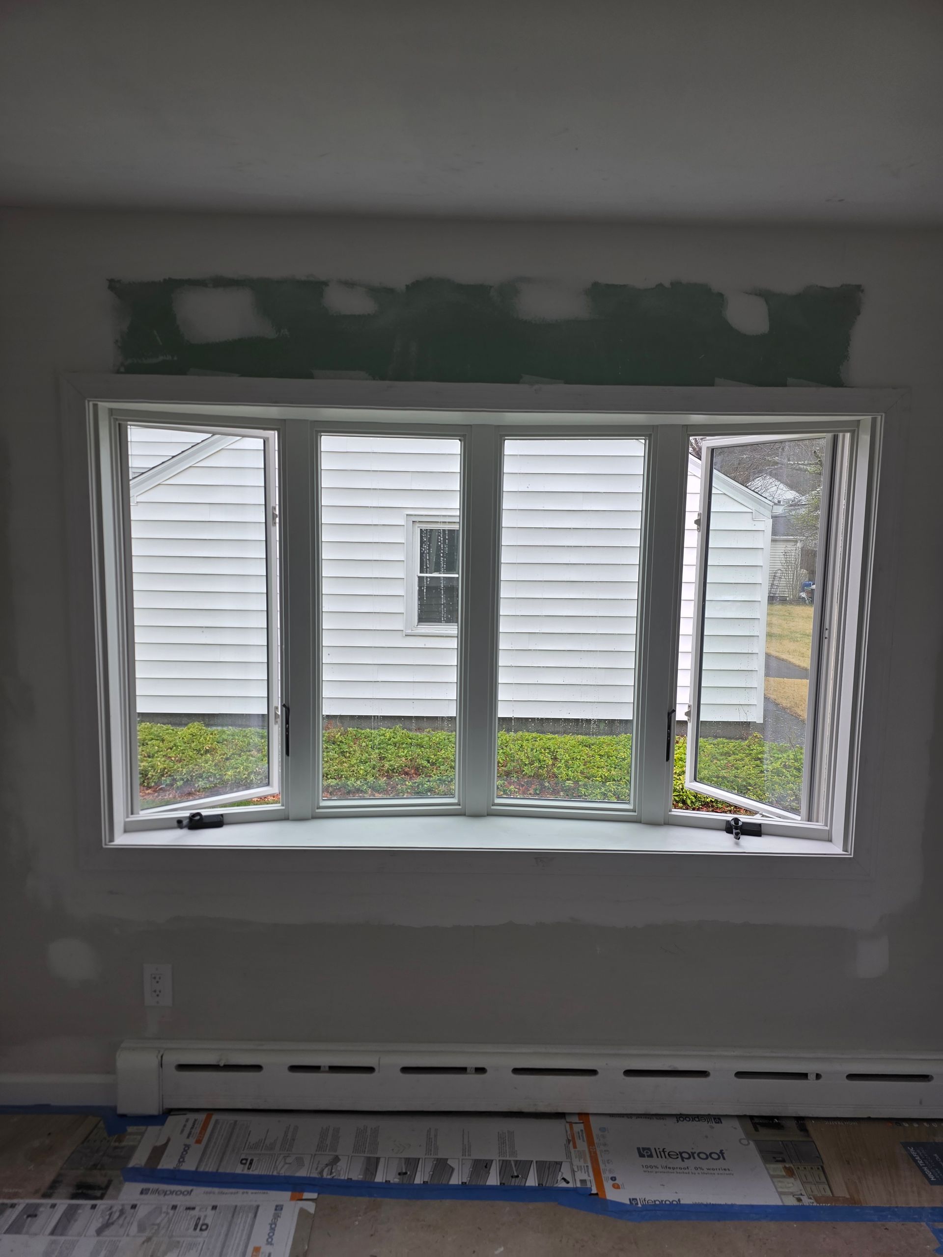 A window in a room with a white house in the background.