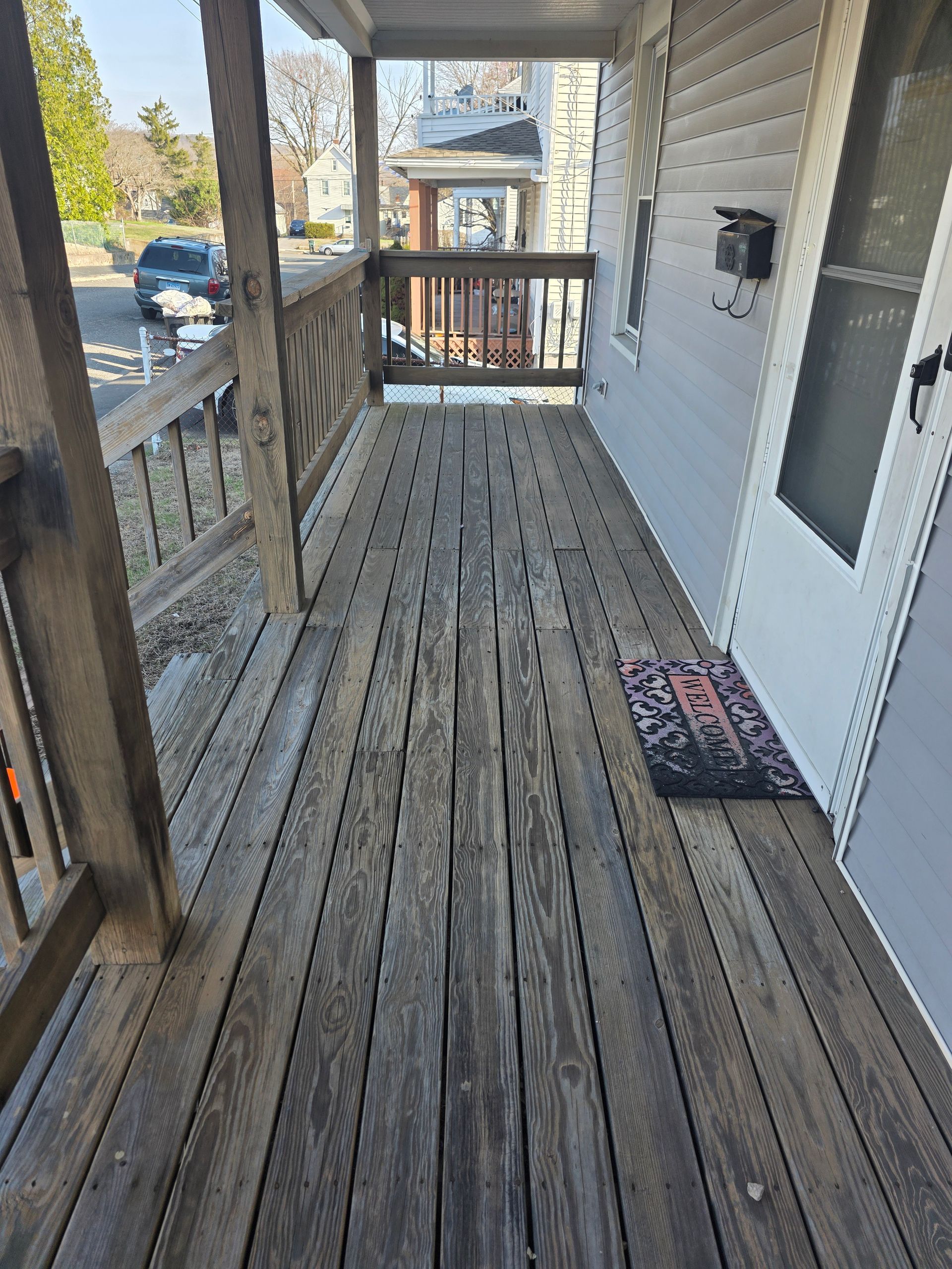 A wooden porch with a door and stairs leading to it.