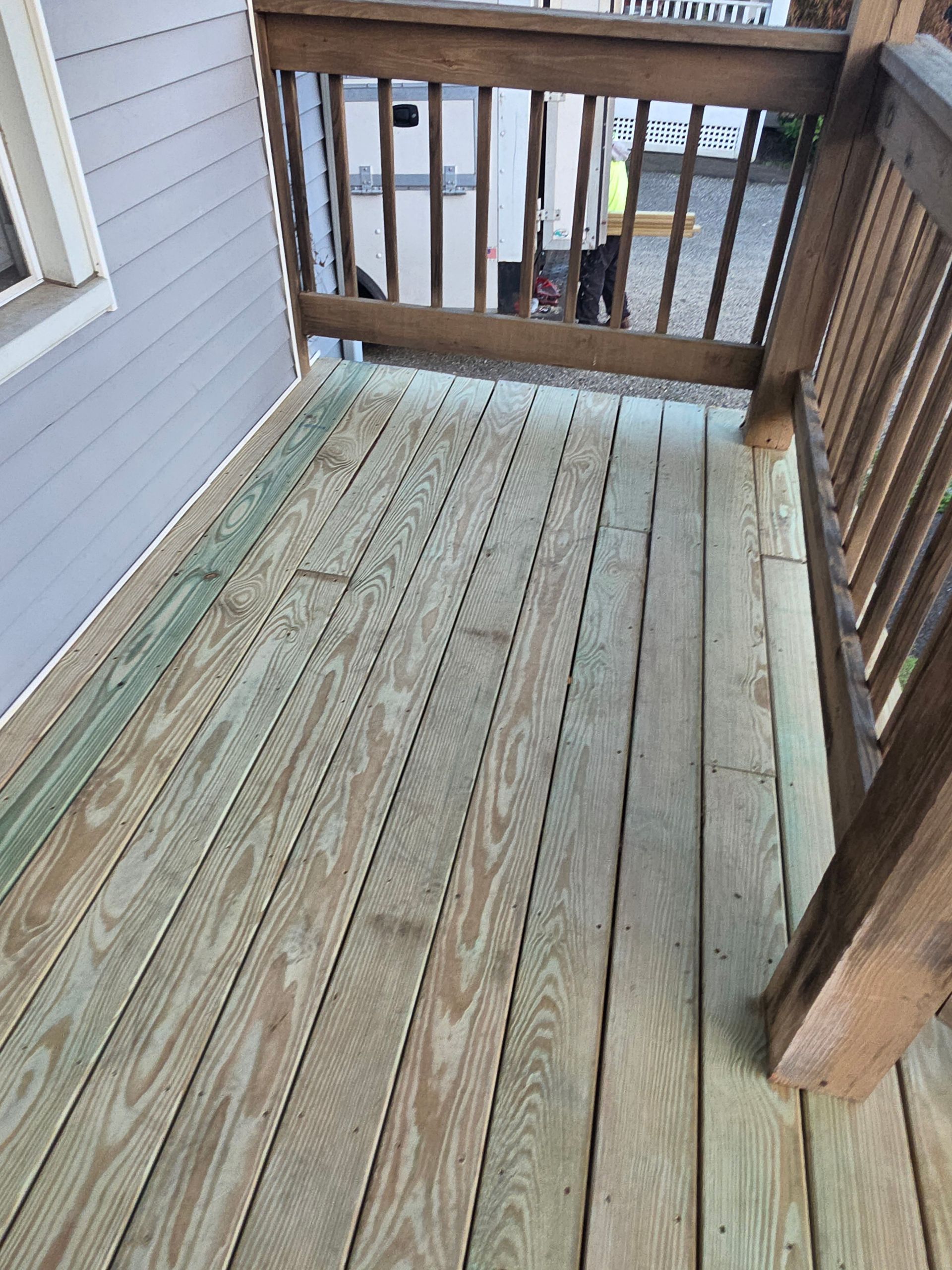 A wooden deck with a railing on the side of a house.