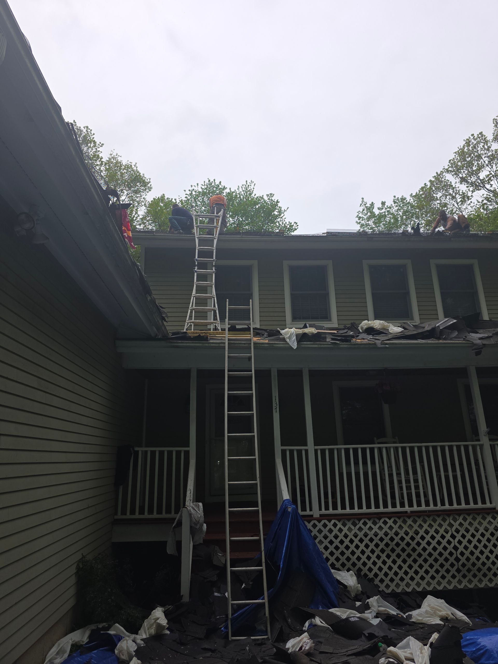 A man on a ladder is working on the roof of a house.