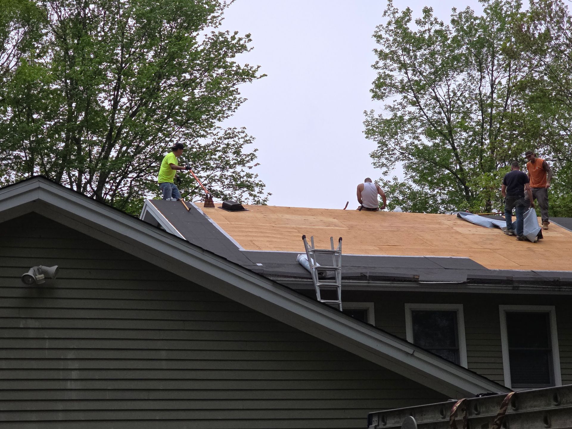 A group of people are working on the roof of a house.