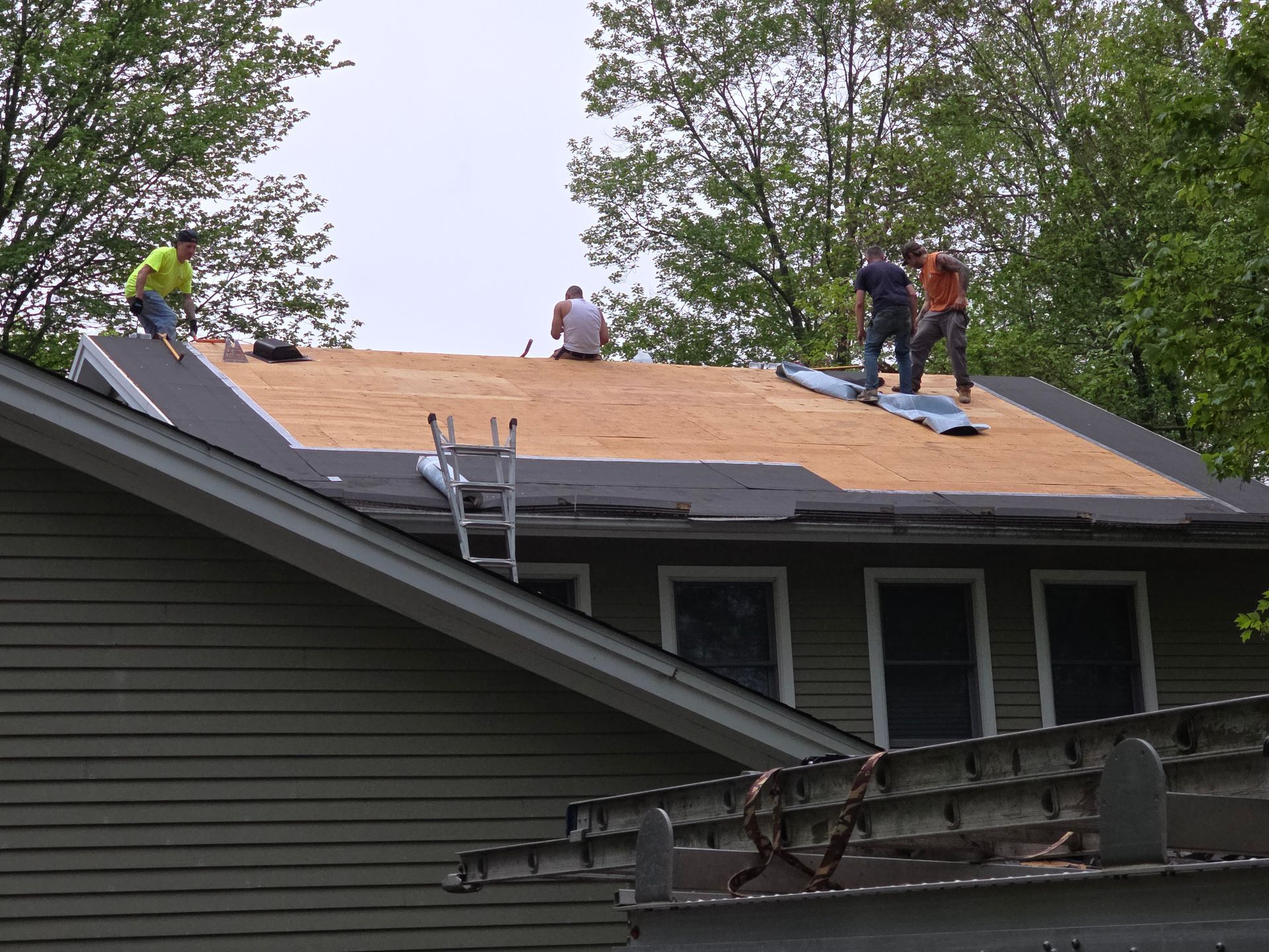A group of men are working on the roof of a house