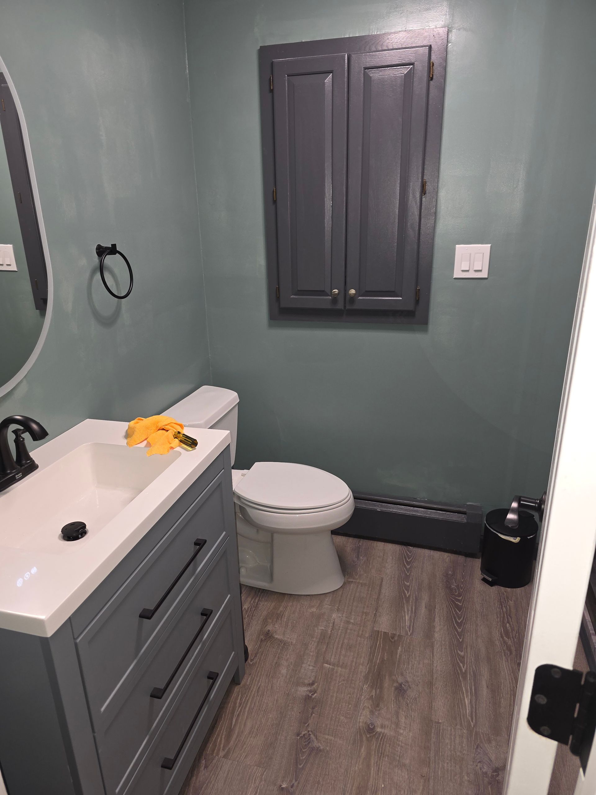 A bathroom with a toilet , sink and mirror.