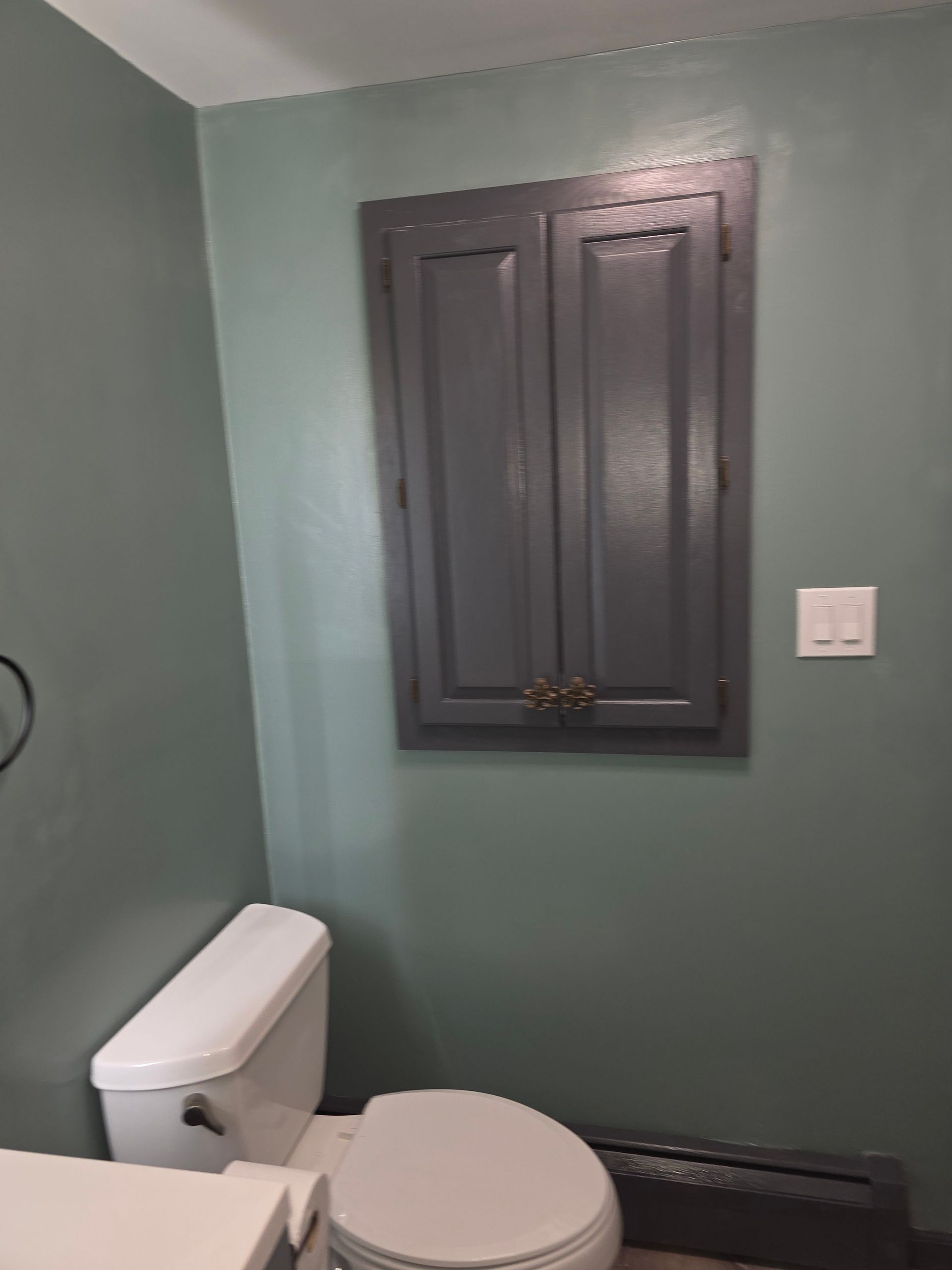 A bathroom with a toilet and a cabinet above it