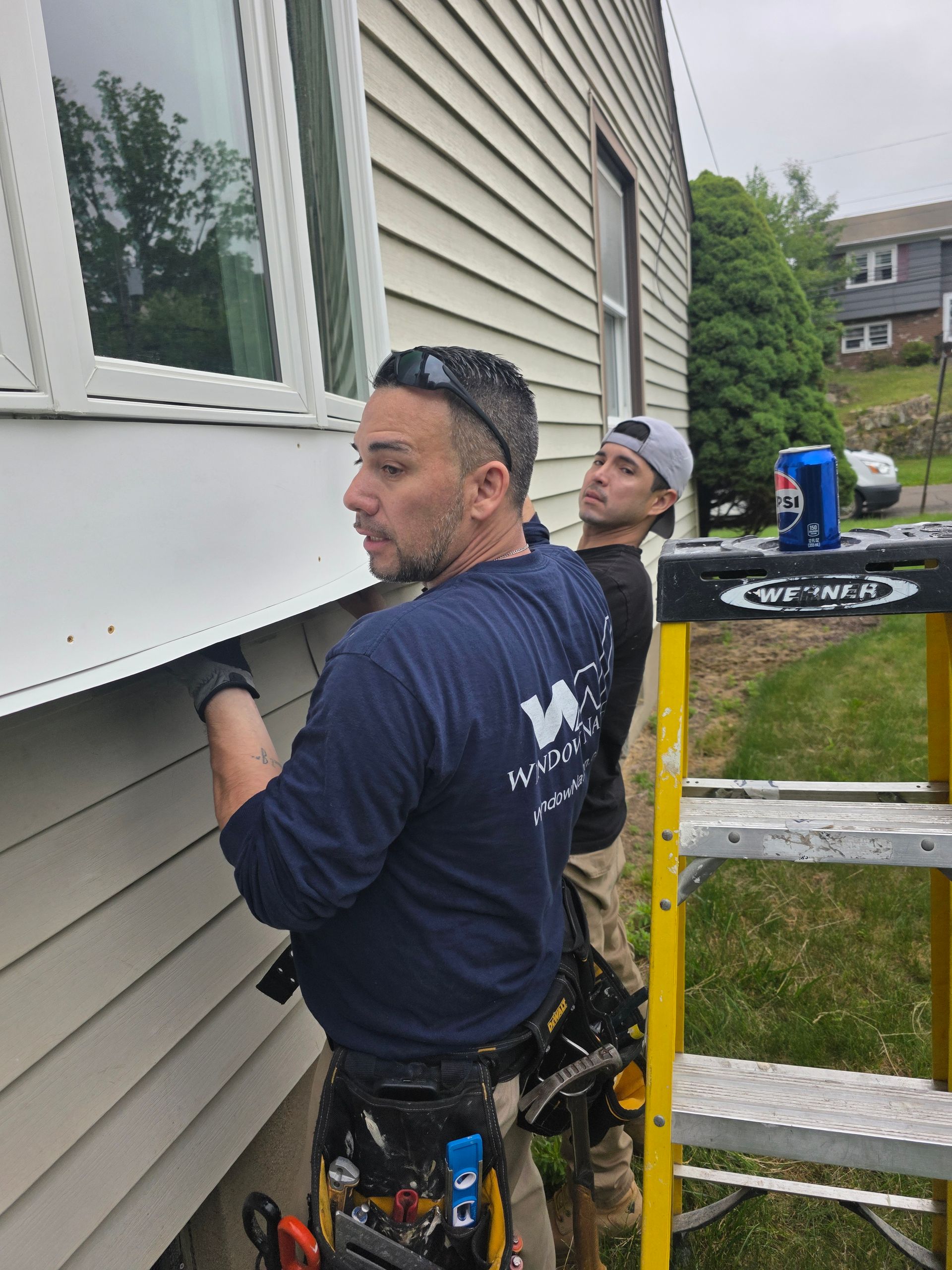 Two men are working on the side of a house.