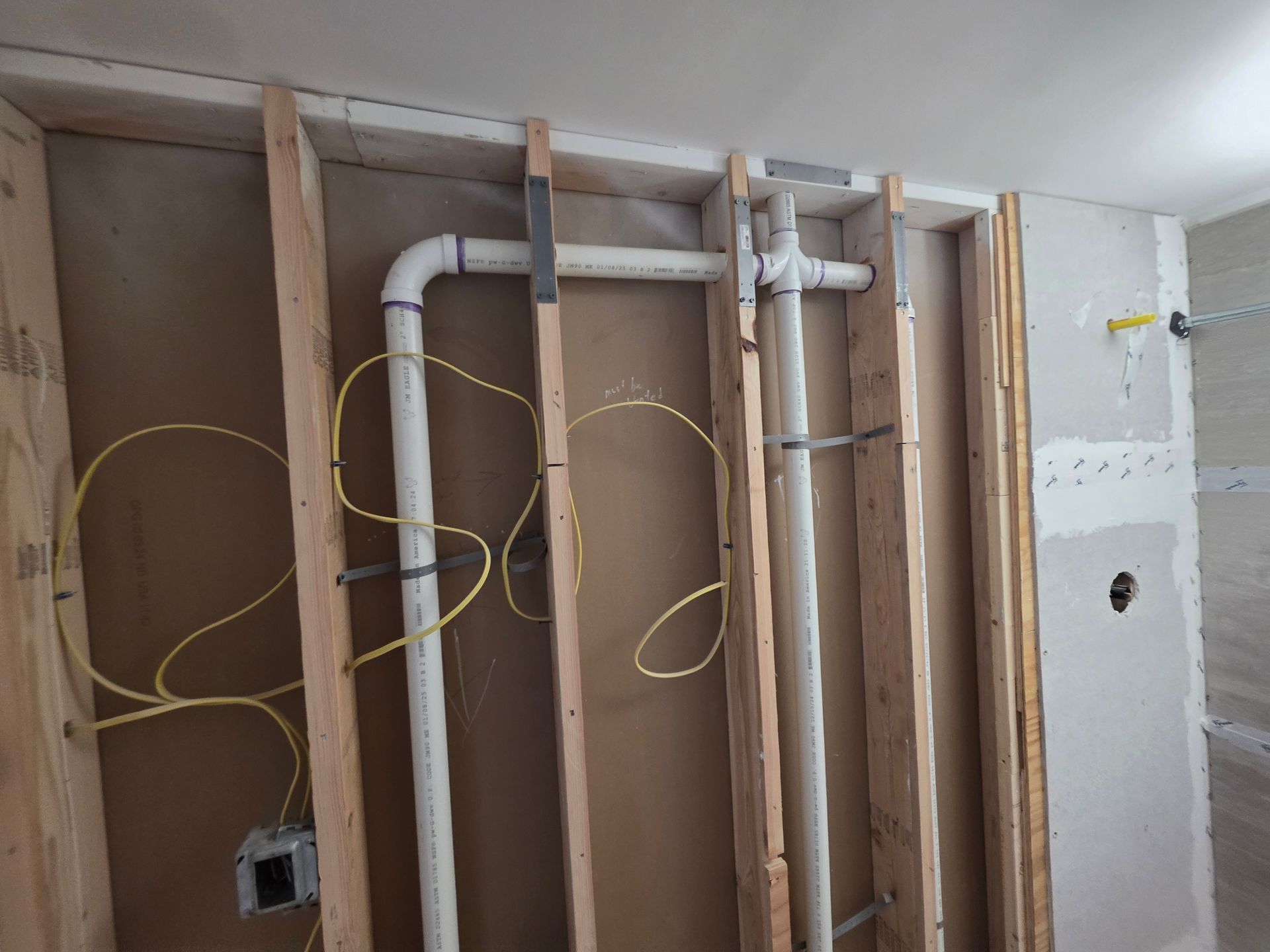 A wooden wall with pipes and wires coming out of it