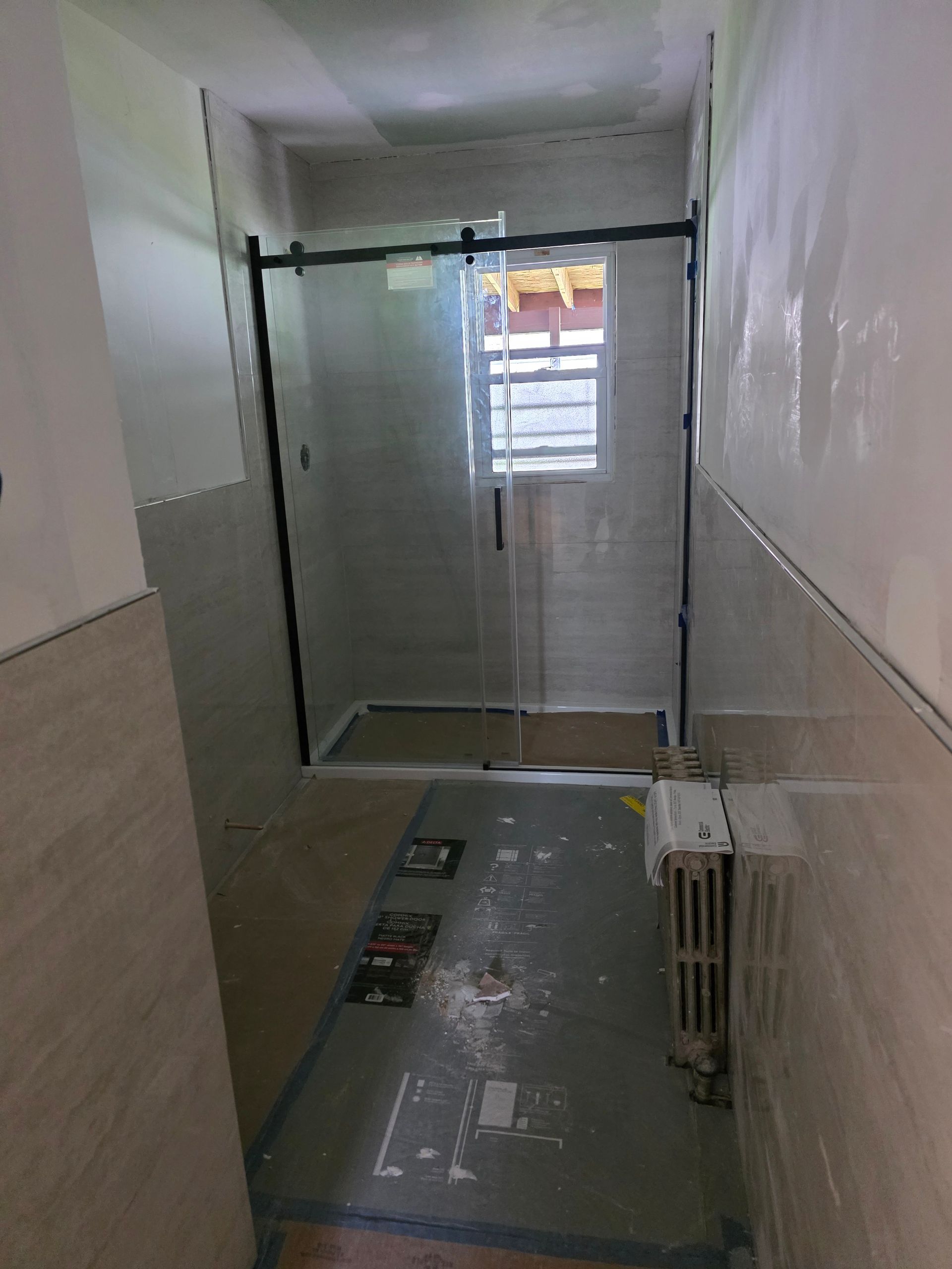 A bathroom with a sliding glass shower door and a radiator.