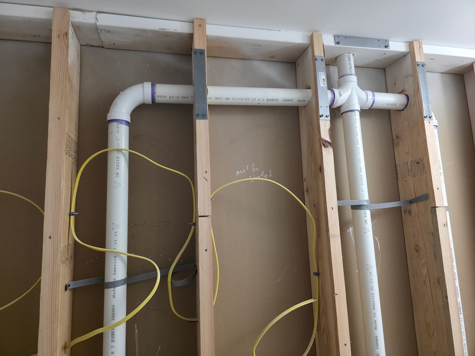 A wall with a bunch of pipes and wires coming out of it