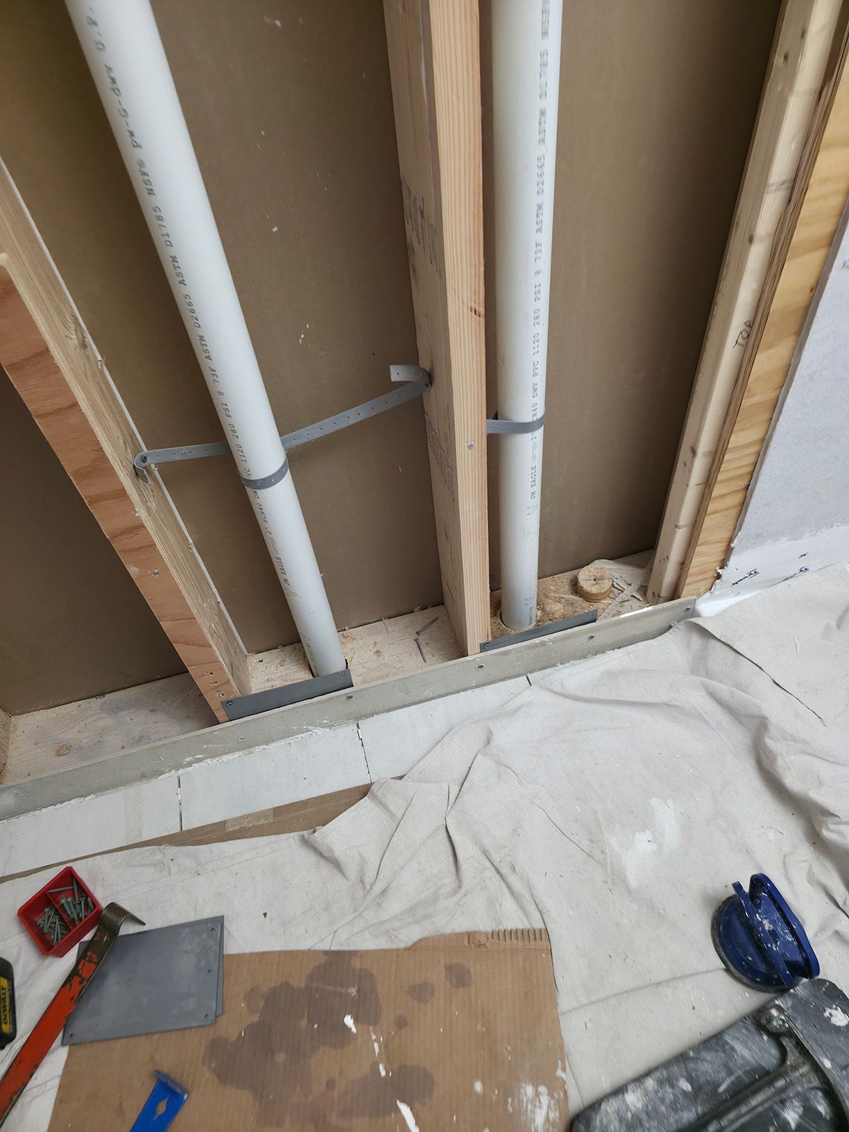 A couple of pipes are being installed in a wall.
