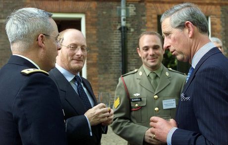 Dr. Dombroski, King Charles of England, and a group of men in suits and military uniforms are talking to each other.