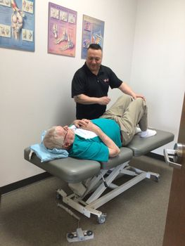 A man is laying on a table while another man stands behind him