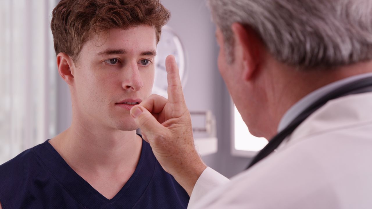 Man doing an eye movement exam for a doctor
