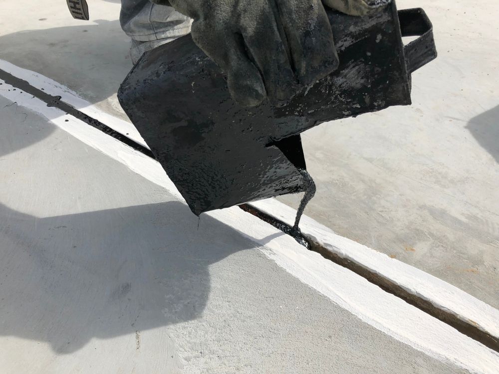 Worker Pouring Black Sealant Into a Crack on a Light Gray Surface — Consider It Sealed Waterproofing in Crangan Bay, NSW
