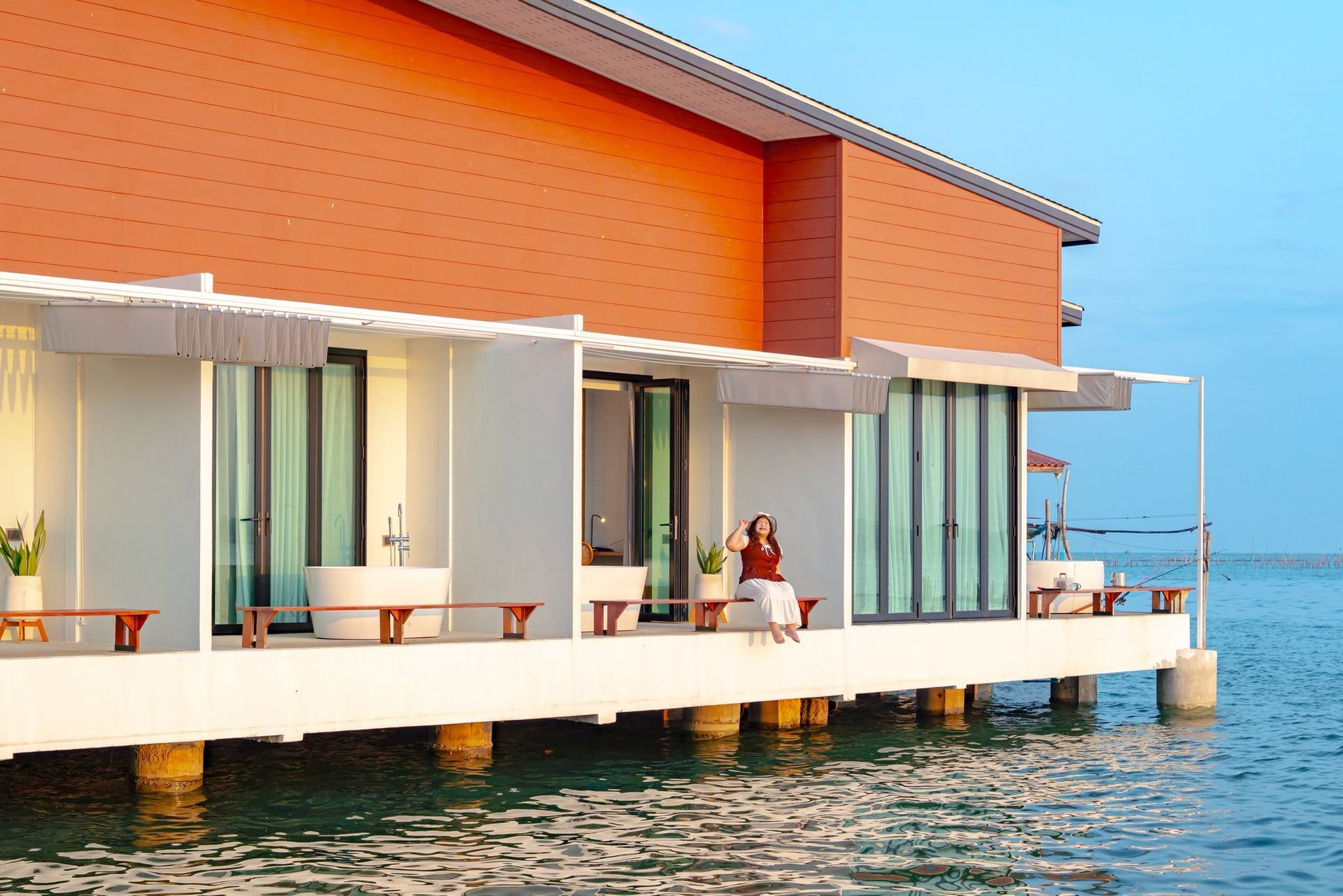 Modern overwater villa with orange walls and white decks above clear blue water