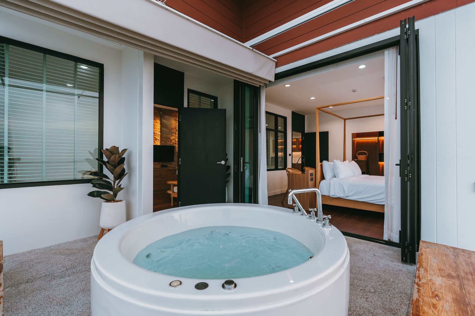 Modern patio with a round hot tub leading into a bedroom through open sliding doors.