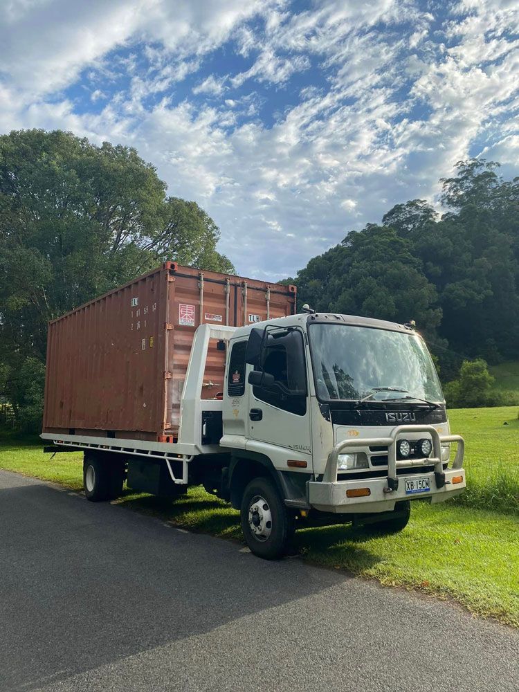 A White Truck With A Red Container On The Back Is Parked On The Side Of The Road — Ries Trucking in Gowrie Mountain, QLD