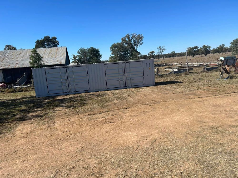 Large White Container Is Sitting In The Middle Of A Dirt Field — Ries Trucking in Gowrie Mountain, QLD