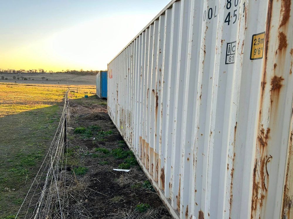 A Row Of Shipping Containers Are Sitting Next To Each Other In A Field — Ries Trucking in Gowrie Mountain, QLD