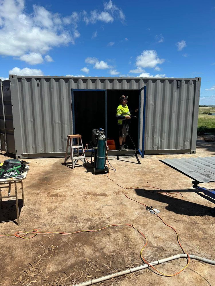 A Man Is Welding In A Shipping Container — Ries Trucking in Gowrie Mountain, QLD