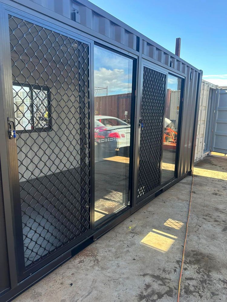 A Shipping Container With Sliding Glass Doors And A Chain Link Fence — Ries Trucking in Gowrie Mountain, QLD