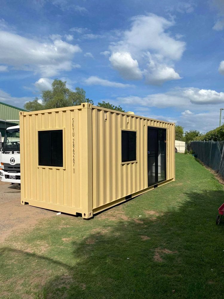 A Shipping Container Is Sitting On Top of A Lush Green Field — Ries Trucking in Gowrie Mountain, QLD