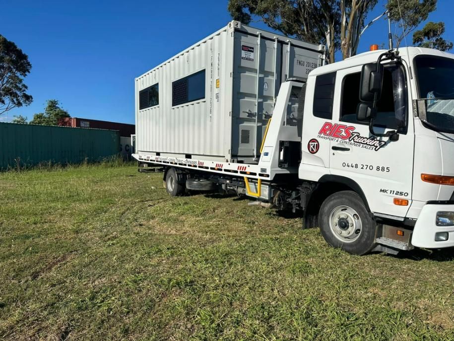 A Tow Truck Is Towing A Shipping Container In A Grassy Field — Ries Trucking in Millmerran, QLD