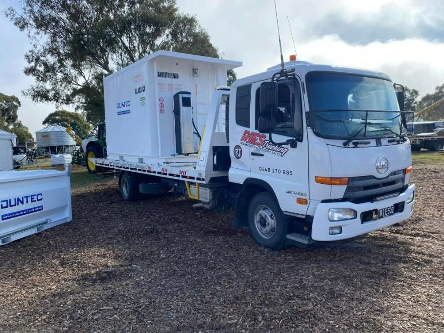 A White Truck With A Trailer Attached To It Is Parked In A Dirt Field — Ries Trucking in Dalby, QLD