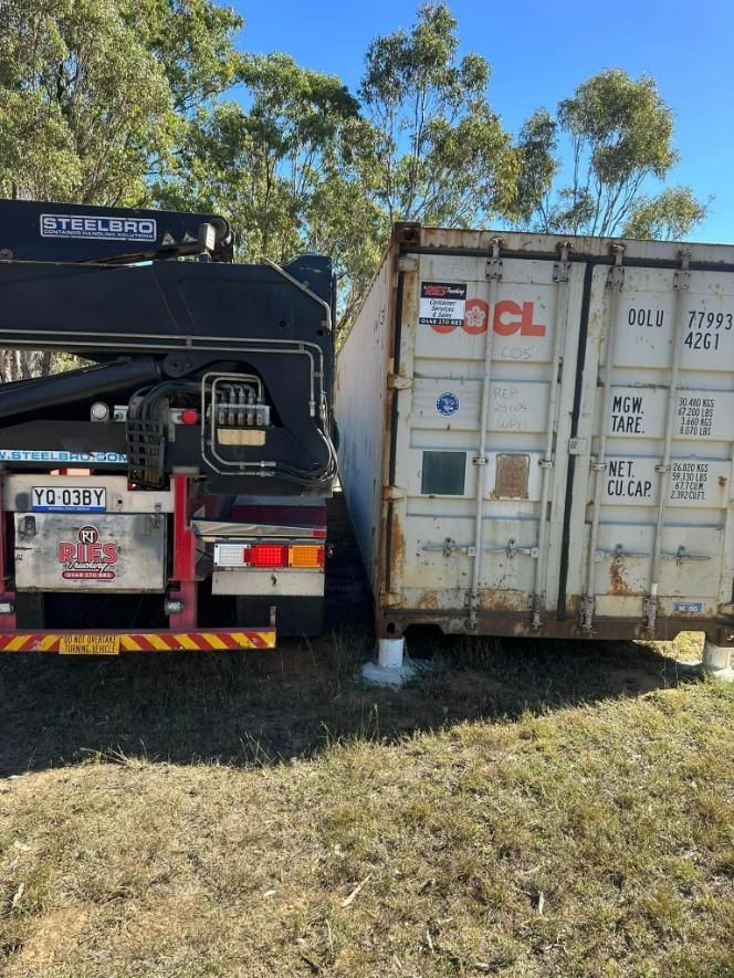 A Truck With A Crane Attached To It Is Parked Next To A Shipping Container — Ries Trucking in Kingaroy, QLD