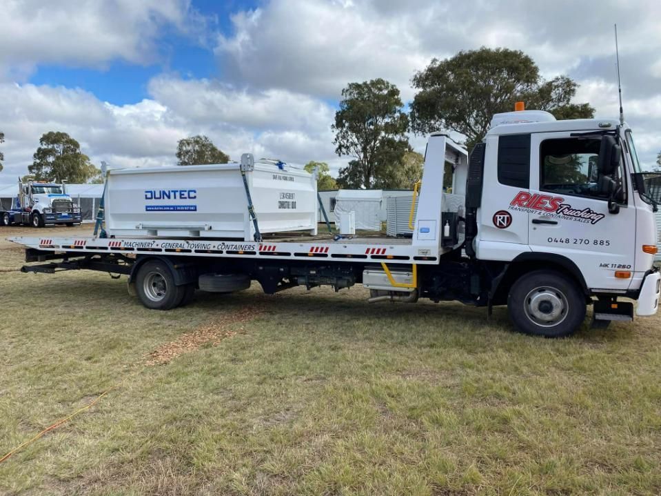 A White Tow Truck Is Parked In A Grassy Field — Ries Trucking in Kingaroy, QLD