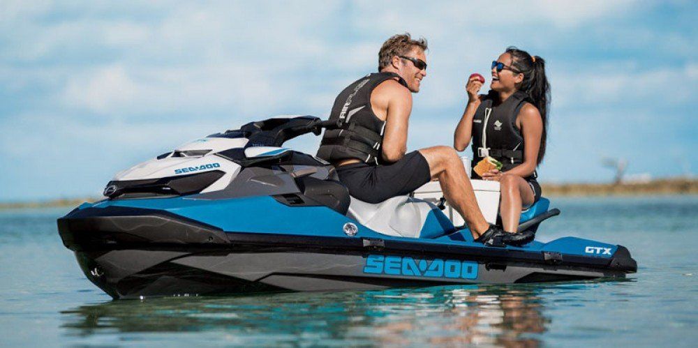 Man and woman smiling while riding on jet ski