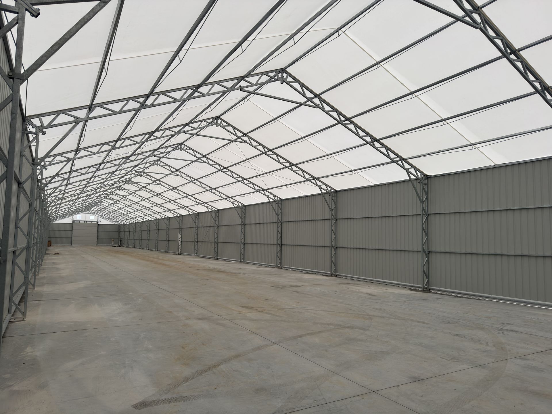 Didelio, tuščio pramoninio pastato su metaliniu karkasu, sienomis ir stogu viduje.