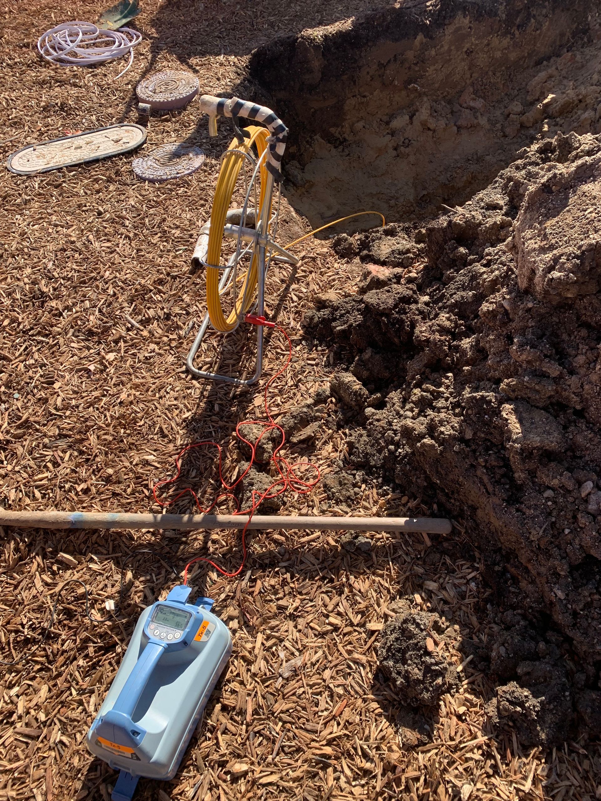 A blue container is sitting in the dirt next to a hole in the ground.