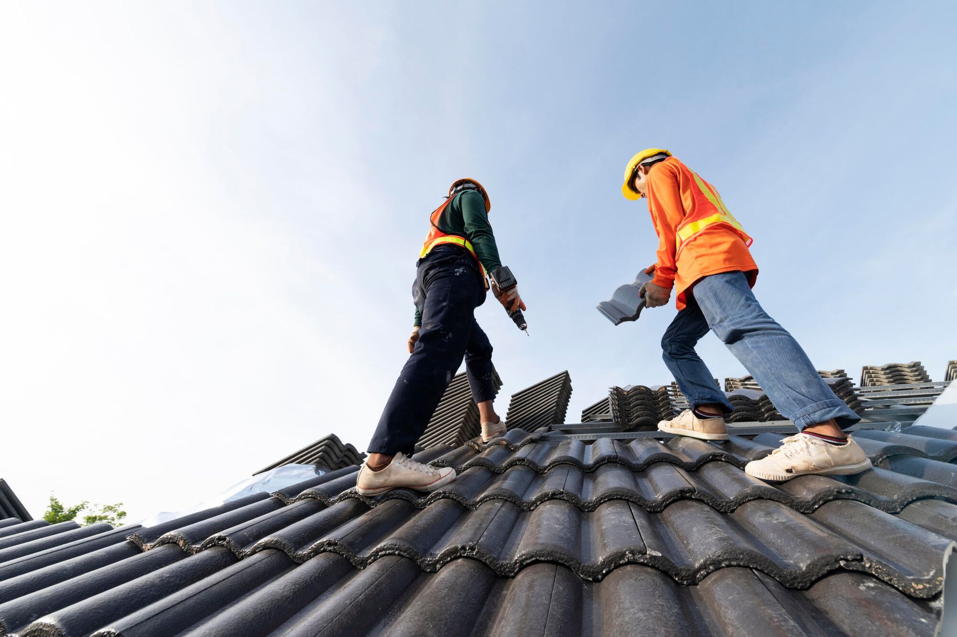 Two construction workers are working on the roof of a house.