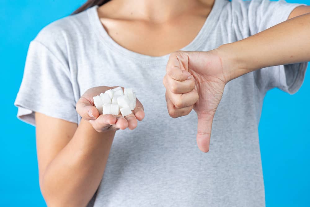 a woman is holding a pile of sugar cubes and giving a thumbs down sign .