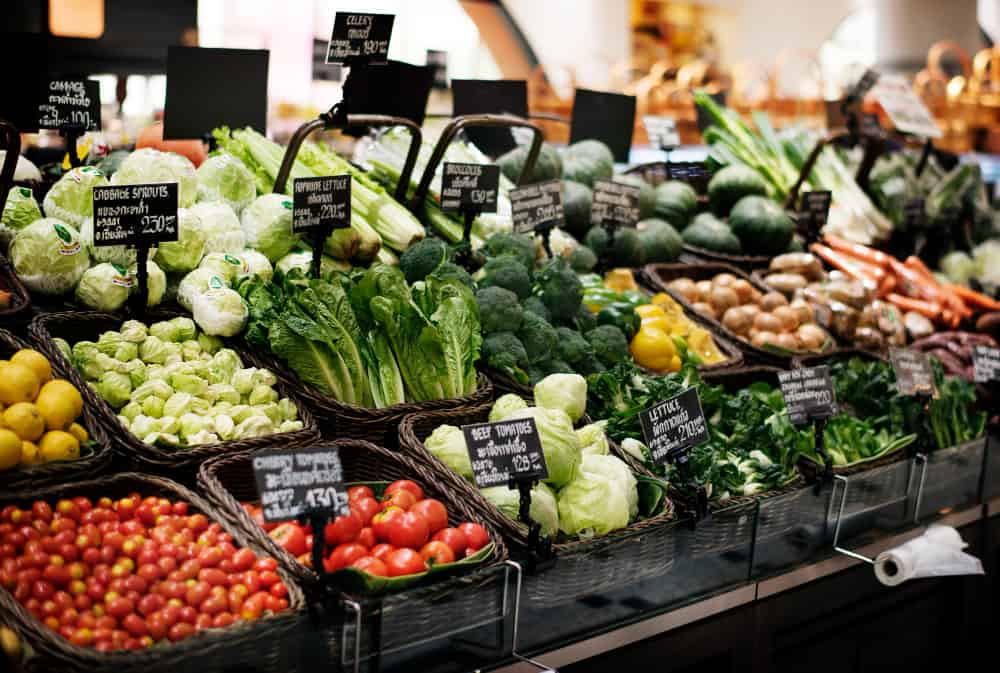 a variety of vegetables are displayed on a shelf in a grocery store .